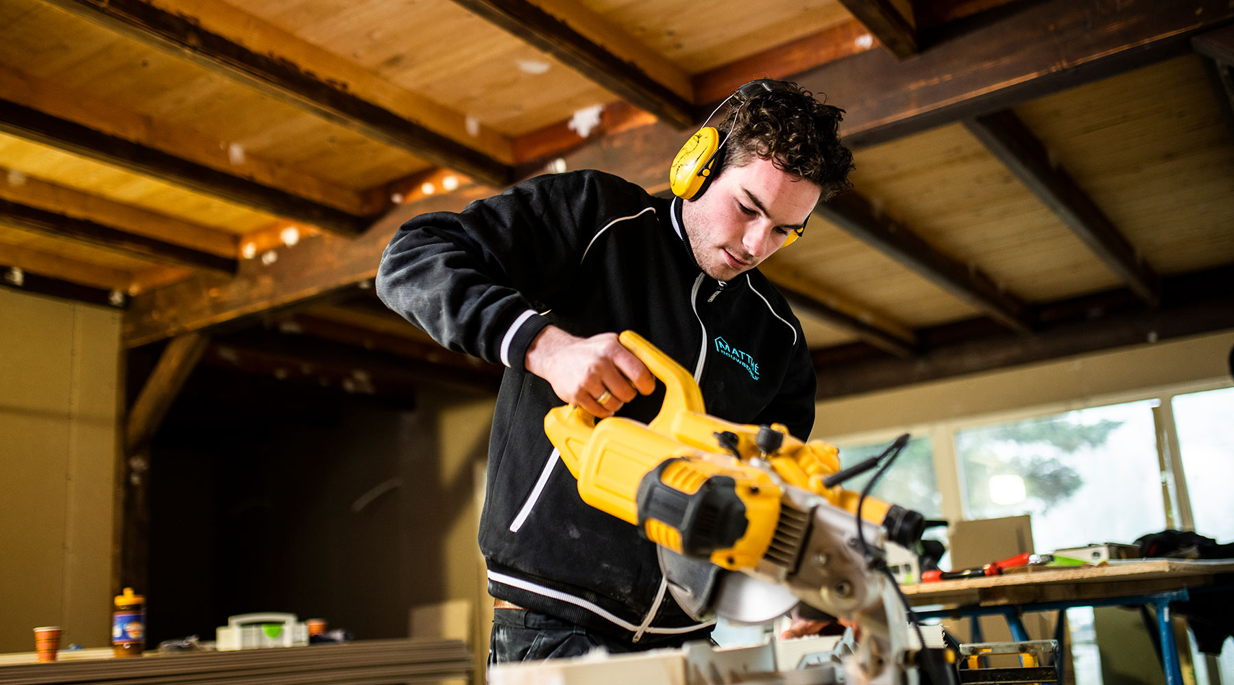 Medewerker Bouwbedrijf Matthé op een afkortzaag bij een uitbouw project